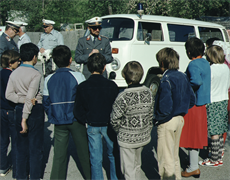 Eine Gruppe von Menschen, die vor einem Polizeiwagen stehen